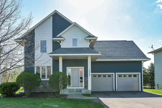view of front of house with asphalt driveway, an attached garage, a shingled roof, and stone siding
