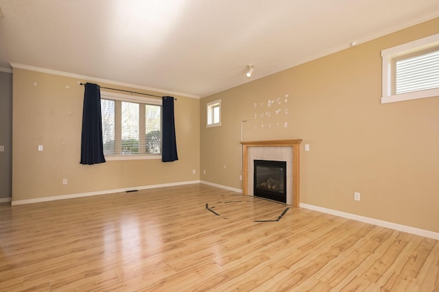 unfurnished living room featuring crown molding, light wood-style floors, a fireplace, and baseboards