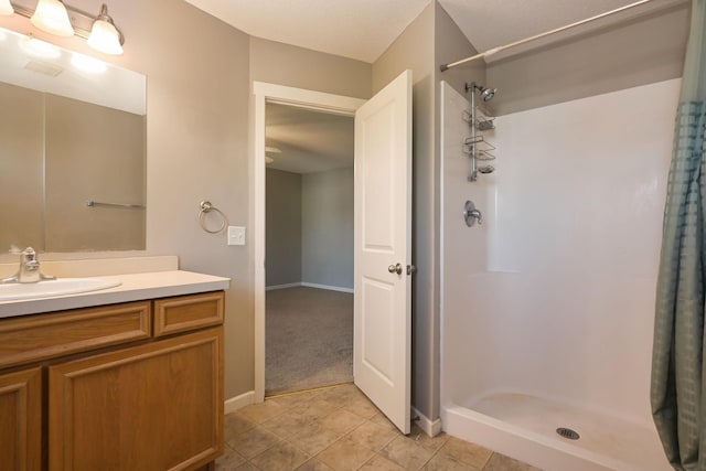 full bathroom featuring a stall shower, vanity, tile patterned flooring, and baseboards
