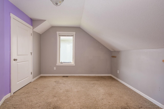 additional living space with carpet flooring, lofted ceiling, and baseboards