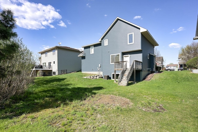 rear view of house with stairway, a wooden deck, and a lawn
