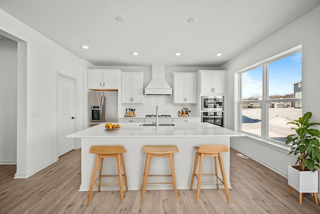 15920 116th Ave N, Dayton, MN 55369 - kitchen with appliances with stainless steel finishes, premium range hood, a breakfast bar, a center island with sink, and recessed lighting
