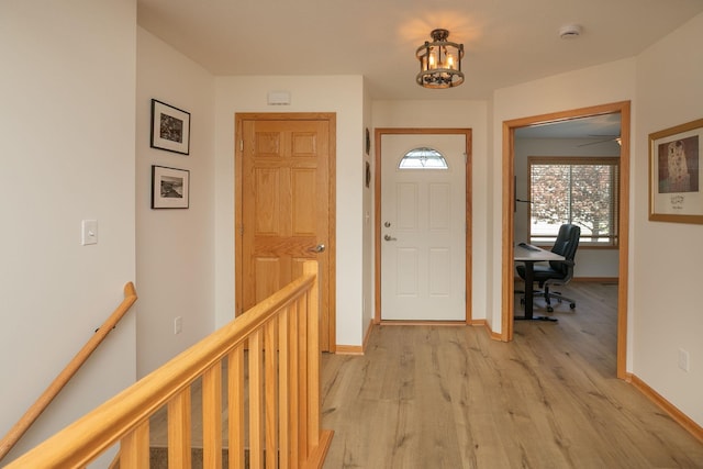 foyer featuring light wood-style flooring, baseboards, and a chandelier