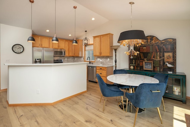 kitchen with stainless steel appliances, light wood-style floors, backsplash, light countertops, and lofted ceiling