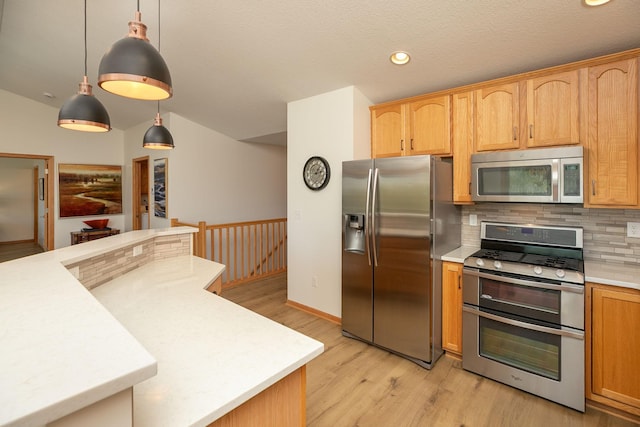 kitchen featuring stainless steel appliances, light countertops, decorative backsplash, light wood-style flooring, and pendant lighting