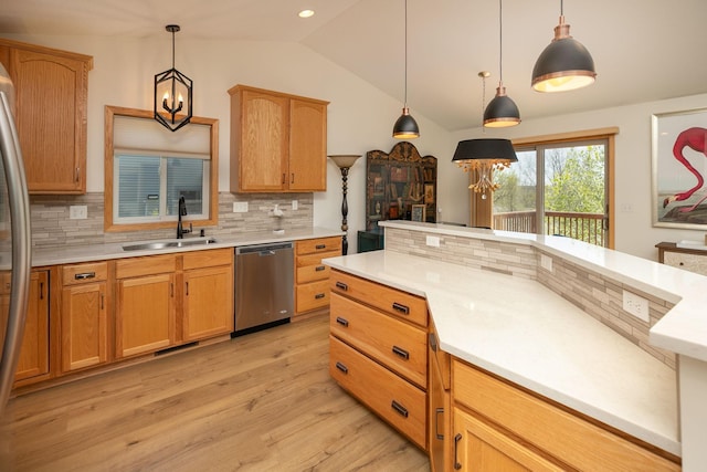 kitchen featuring stainless steel appliances, a sink, light wood finished floors, light countertops, and backsplash