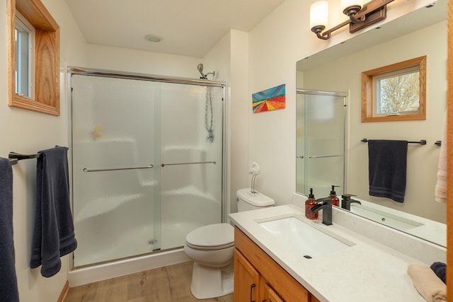 full bath featuring wood finished floors, a shower stall, toilet, and vanity