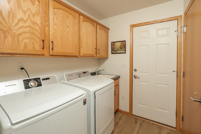 laundry area with separate washer and dryer, light wood-type flooring, and cabinet space