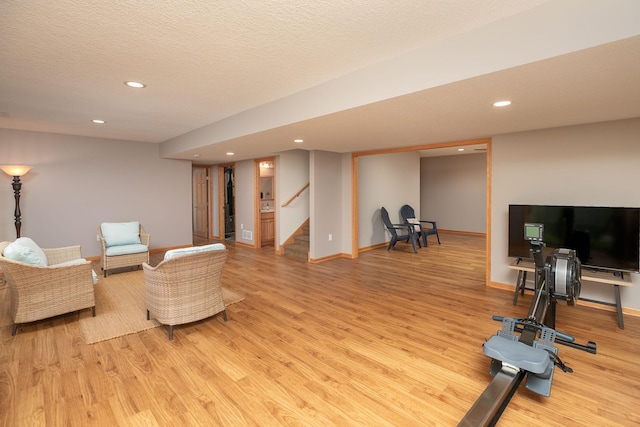 living area featuring light wood-style floors, recessed lighting, stairs, baseboards, and a textured ceiling