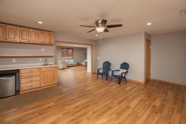 kitchen with light countertops, light wood finished floors, ceiling fan, recessed lighting, and a textured ceiling