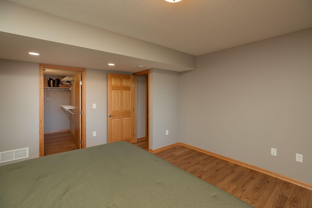 bedroom featuring wood finished floors, recessed lighting, baseboards, a spacious closet, and a closet