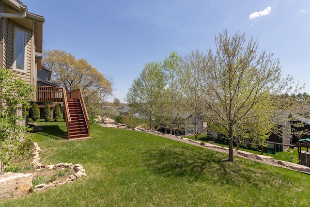 view of green lawn featuring stairway and a deck