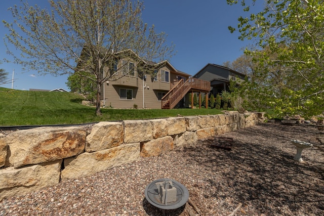 rear view of property with stairs, a deck, and a lawn