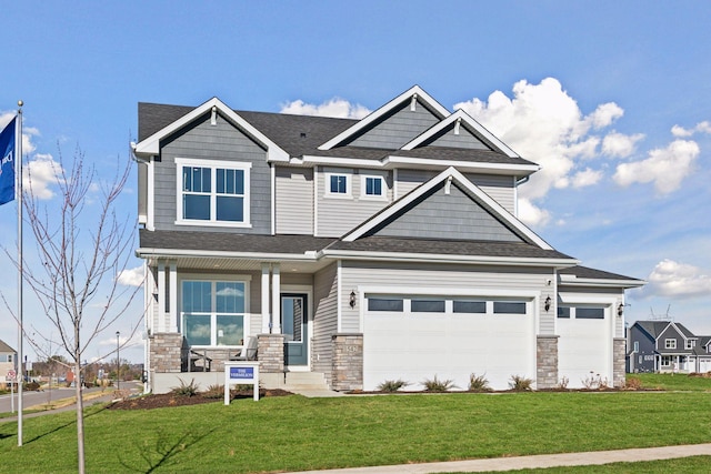 craftsman house featuring stone siding, a front yard, an attached garage, and a shingled roof