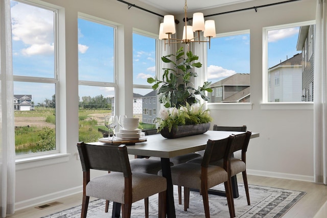 dining area with a chandelier, light wood-type flooring, and baseboards