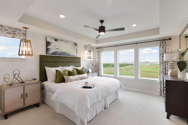 bedroom with a raised ceiling, multiple windows, light carpet, and recessed lighting