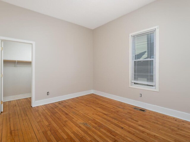 2100 Dupont Ave N, Minneapolis, MN 55411 - unfurnished bedroom with baseboards, hardwood / wood-style floors, a closet, and a spacious closet