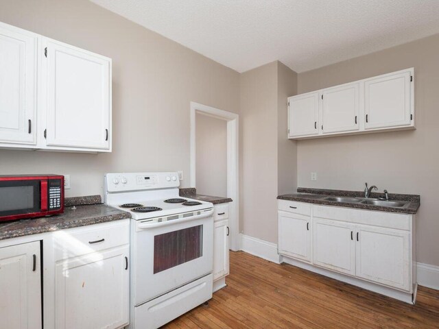 2100 Dupont Ave N, Minneapolis, MN 55411 - kitchen with electric stove, a sink, dark countertops, white cabinets, and light wood finished floors