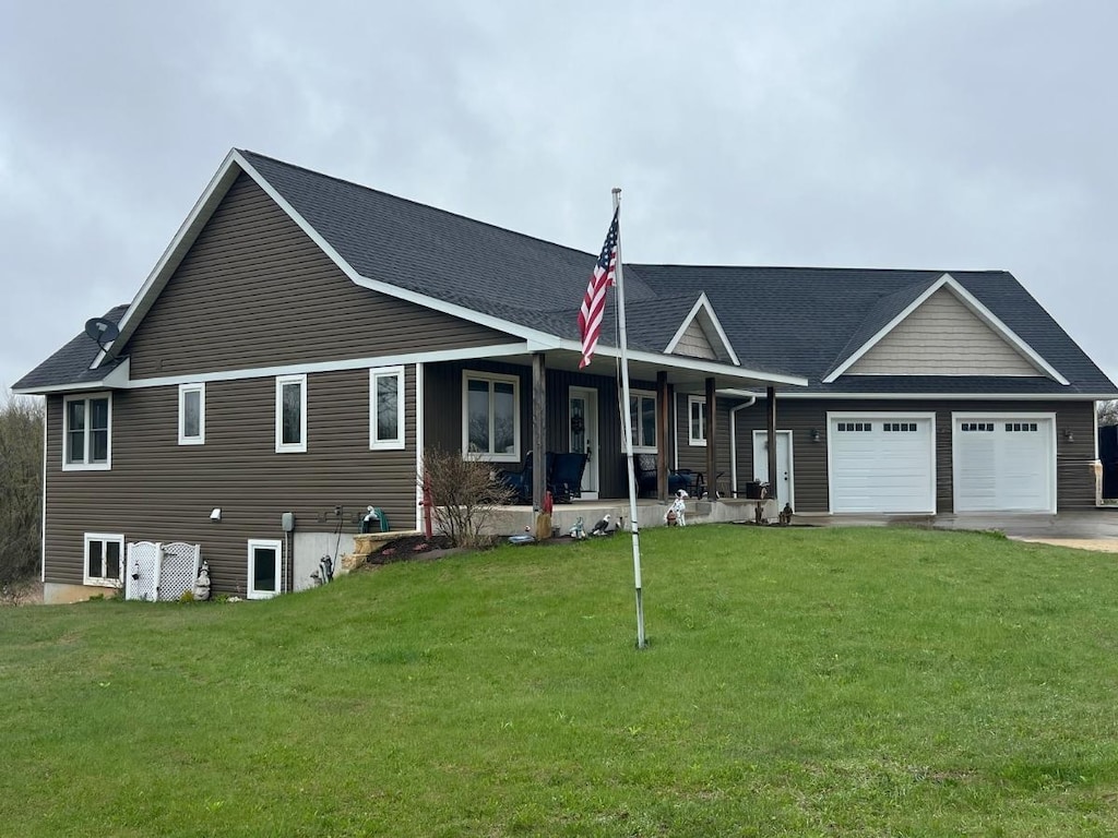 view of front of house featuring a garage, a porch, a front yard, and driveway
