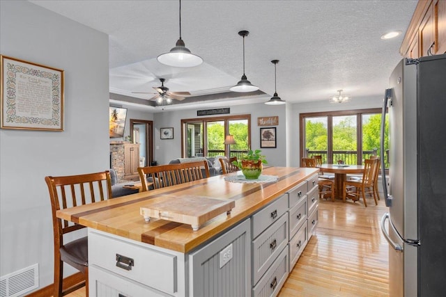 1704 156th St, Erin Prairie Twp, WI 54017 - kitchen with freestanding refrigerator, a textured ceiling, butcher block counters, a center island, and light wood-type flooring