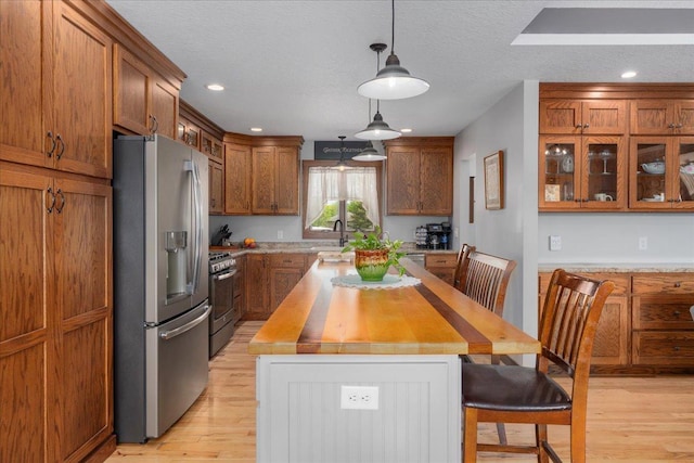 1704 156th St, Erin Prairie Twp, WI 54017 - kitchen featuring appliances with stainless steel finishes, light wood-style flooring, brown cabinets, a kitchen breakfast bar, and a kitchen island