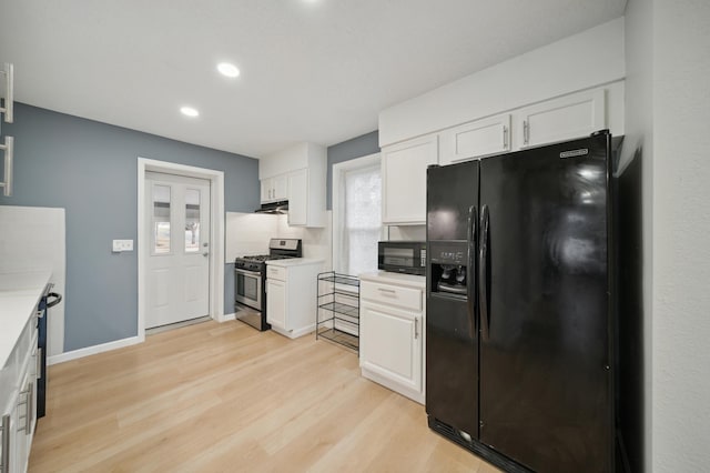 kitchen featuring black appliances, white cabinets, under cabinet range hood, light wood-type flooring, and light countertops