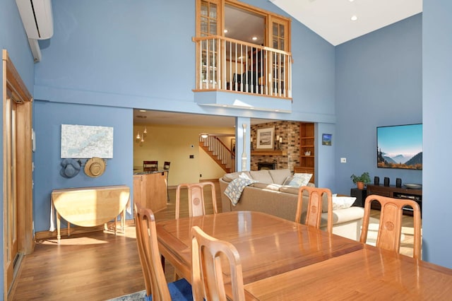 dining area with high vaulted ceiling, wood finished floors, a fireplace, built in shelves, and baseboards