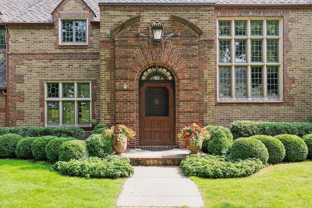entrance to property featuring brick siding and a shingled roof