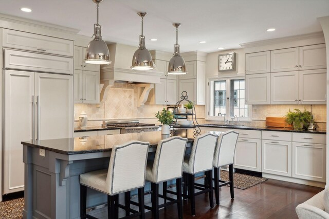 kitchen featuring a kitchen island, a kitchen bar, tasteful backsplash, a sink, and recessed lighting