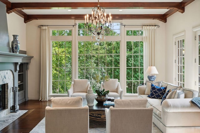 living room featuring beam ceiling, wood finished floors, baseboards, and a chandelier