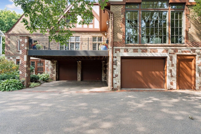 view of front facade featuring a garage, driveway, stone siding, and brick siding