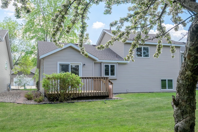 rear view of house featuring a shingled roof, a deck, and a yard