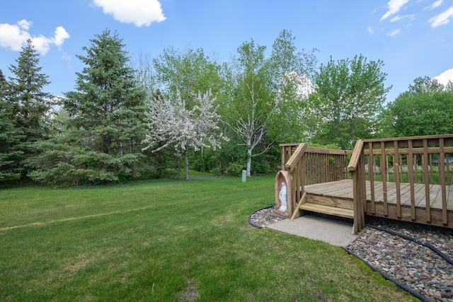 view of green lawn with a deck and view of scattered trees