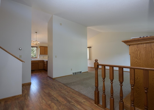 empty room with lofted ceiling, dark wood-style flooring, a chandelier, baseboards, and a sink