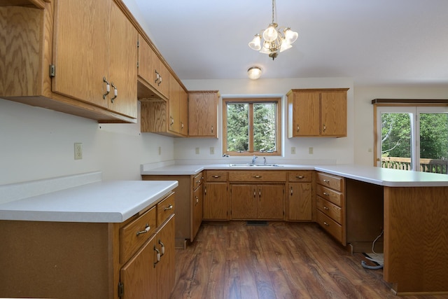 kitchen with a sink, a peninsula, dark wood-style flooring, light countertops, and plenty of natural light