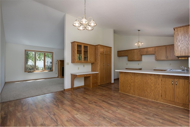 kitchen with a chandelier, a sink, a peninsula, brown cabinetry, and high vaulted ceiling