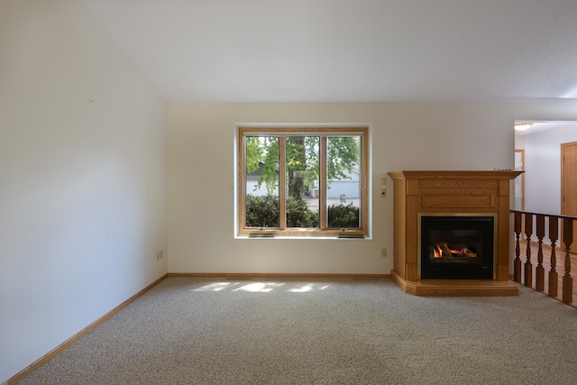 unfurnished living room with carpet floors, baseboards, and a glass covered fireplace