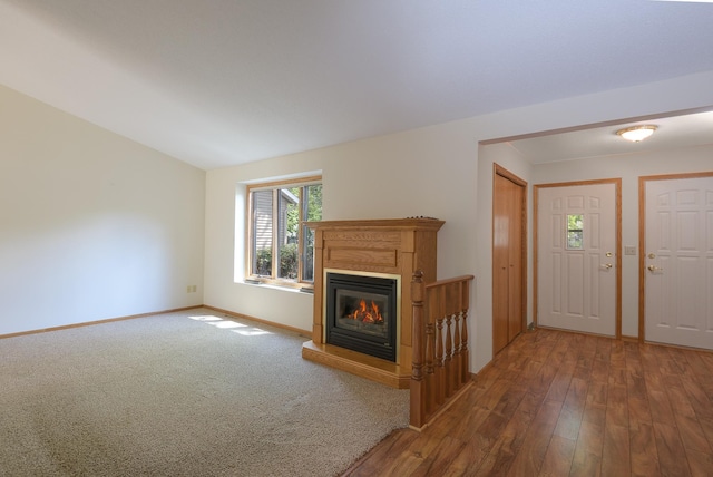 unfurnished living room with a glass covered fireplace, baseboards, and wood finished floors