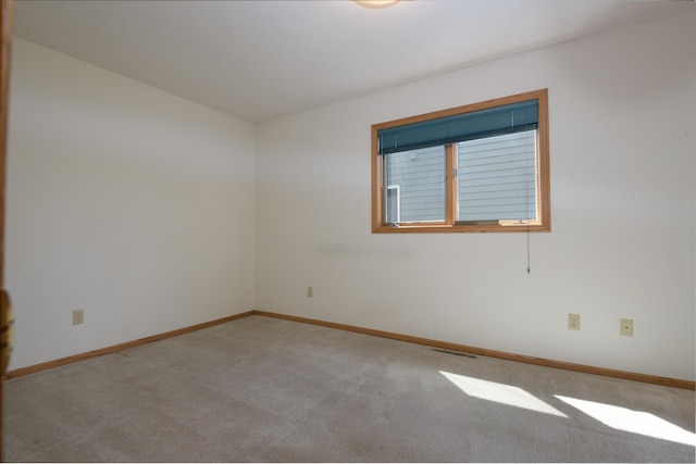 carpeted spare room featuring baseboards