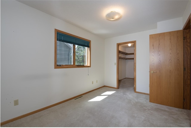 unfurnished bedroom with carpet flooring, baseboards, a spacious closet, and a closet