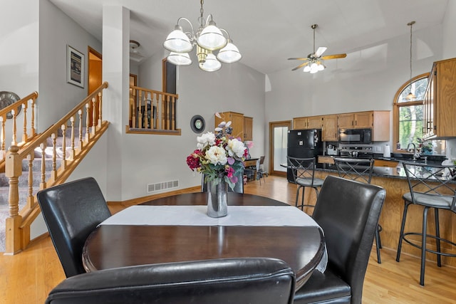 13367 Martin St NW, Andover, MN 55304 - dining space featuring high vaulted ceiling, a ceiling fan, light wood-style floors, a chandelier, and stairs