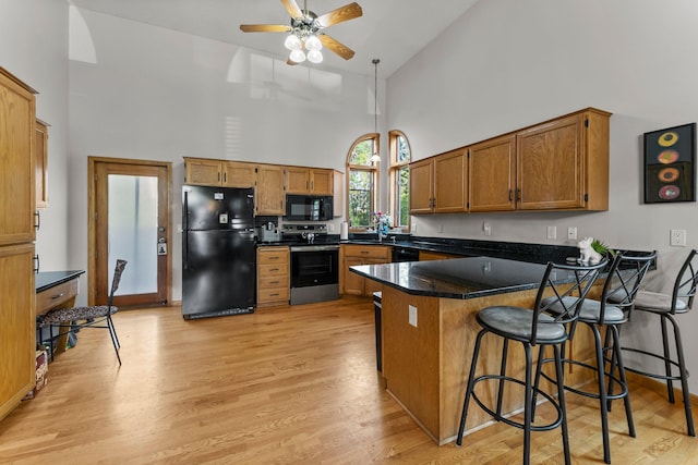 13367 Martin St NW, Andover, MN 55304 - kitchen with black appliances, a peninsula, high vaulted ceiling, brown cabinets, and light wood finished floors