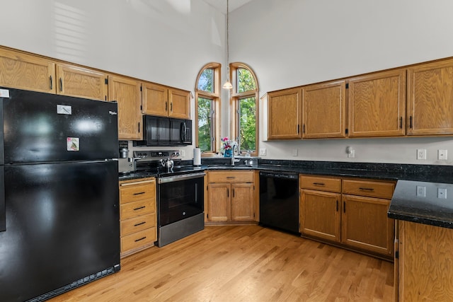 13367 Martin St NW, Andover, MN 55304 - kitchen with black appliances, a sink, a towering ceiling, light wood-style floors, and brown cabinetry