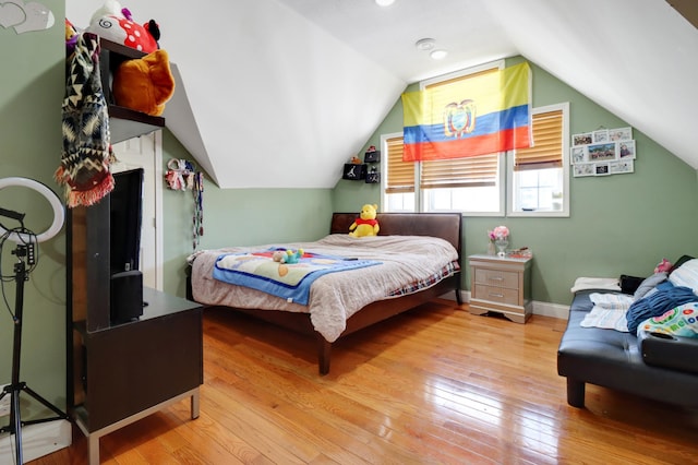 bedroom with hardwood / wood-style flooring, lofted ceiling, and baseboards