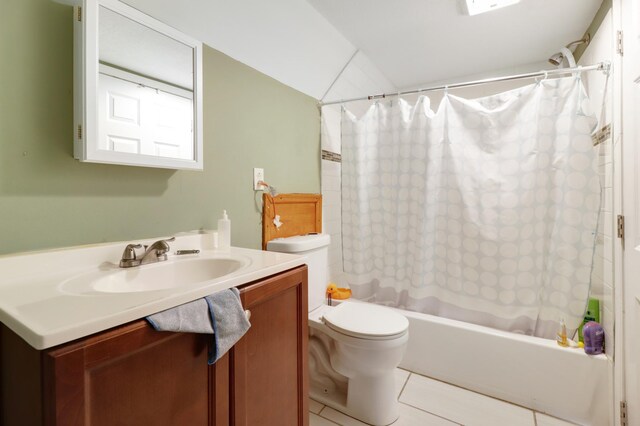 full bathroom with tile patterned floors, shower / bath combo with shower curtain, toilet, vanity, and vaulted ceiling