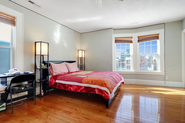 bedroom with wood finished floors, baseboards, and a textured ceiling