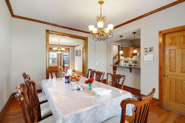 dining area featuring a chandelier, hardwood / wood-style flooring, baseboards, and crown molding