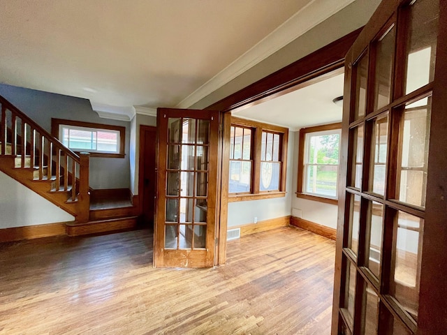 unfurnished room featuring baseboards, wood finished floors, ornamental molding, and stairs