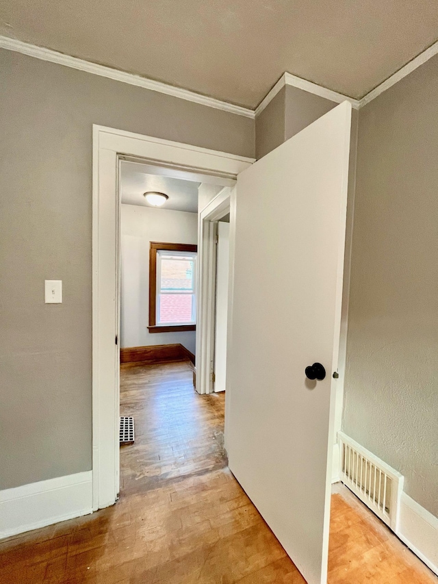hall featuring ornamental molding, wood finished floors, and baseboards