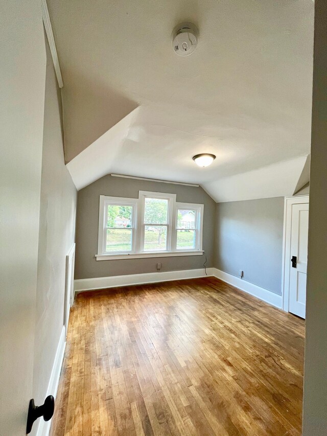 bonus room featuring vaulted ceiling, wood-type flooring, and baseboards